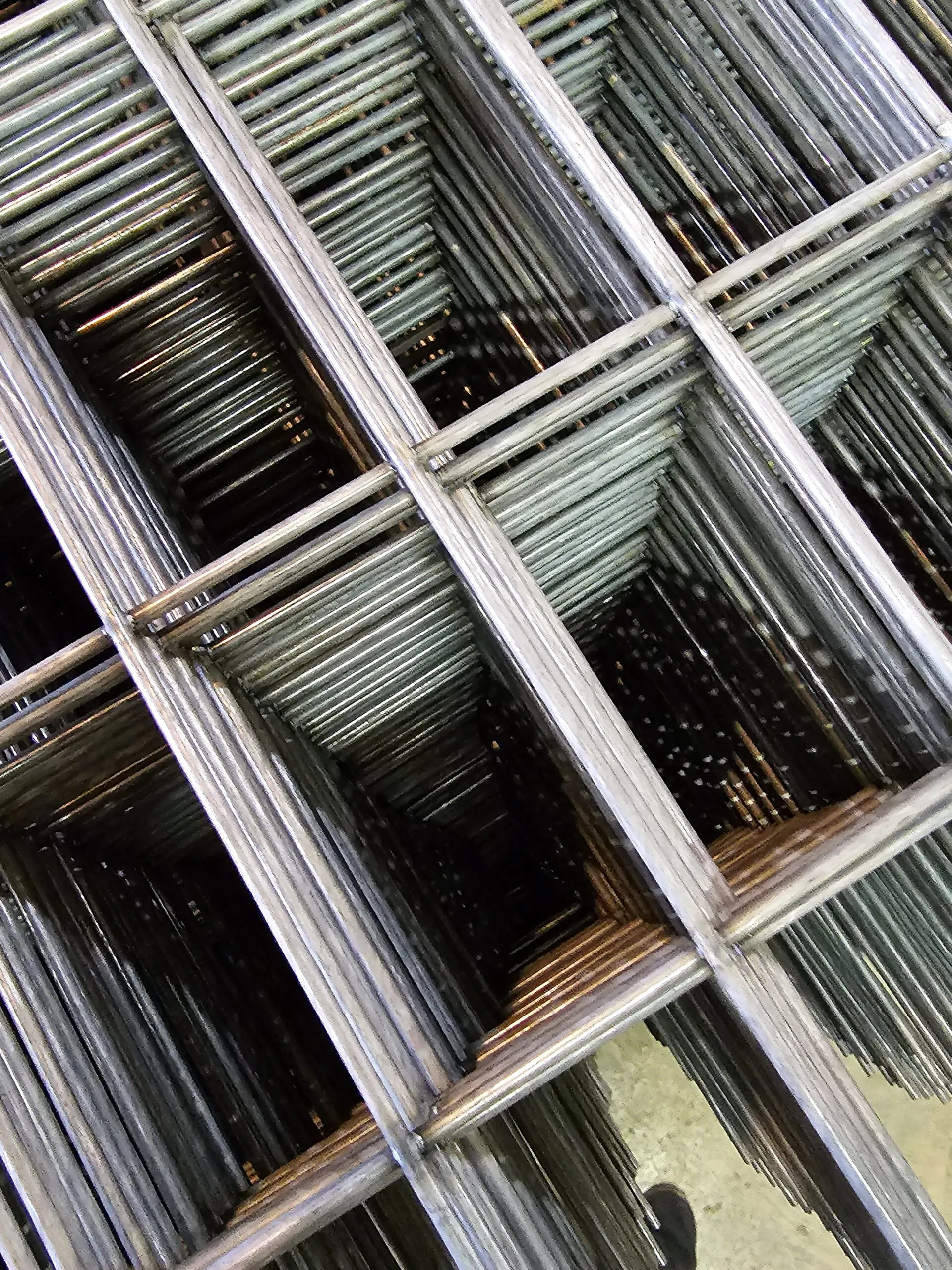 Stacked galvanized steel frames forming geometric pattern in industrial setting